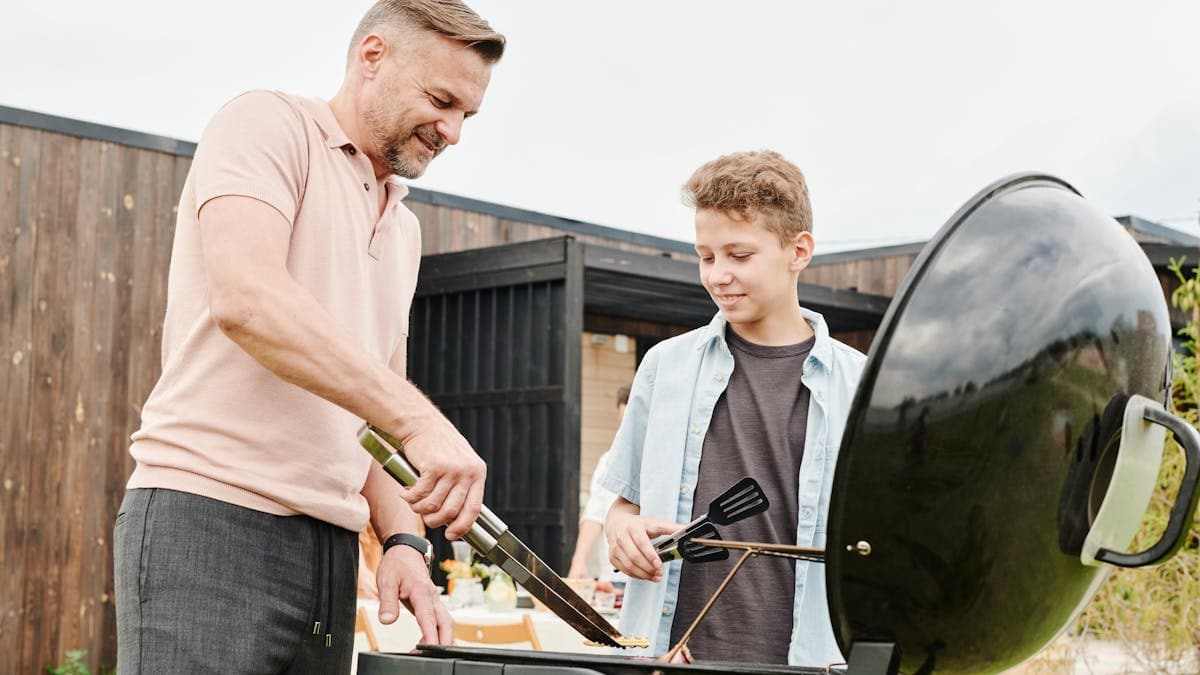 Family gathered around a backyard pellet grill cookout