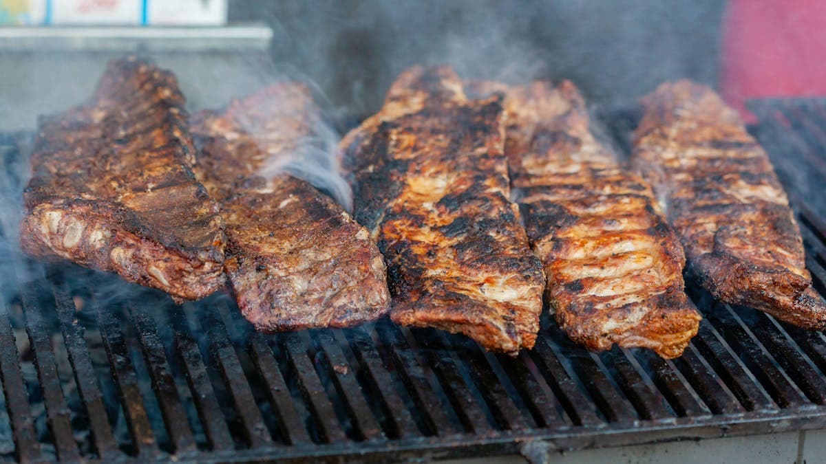 Ribs being seasoned with dry rub on the grill