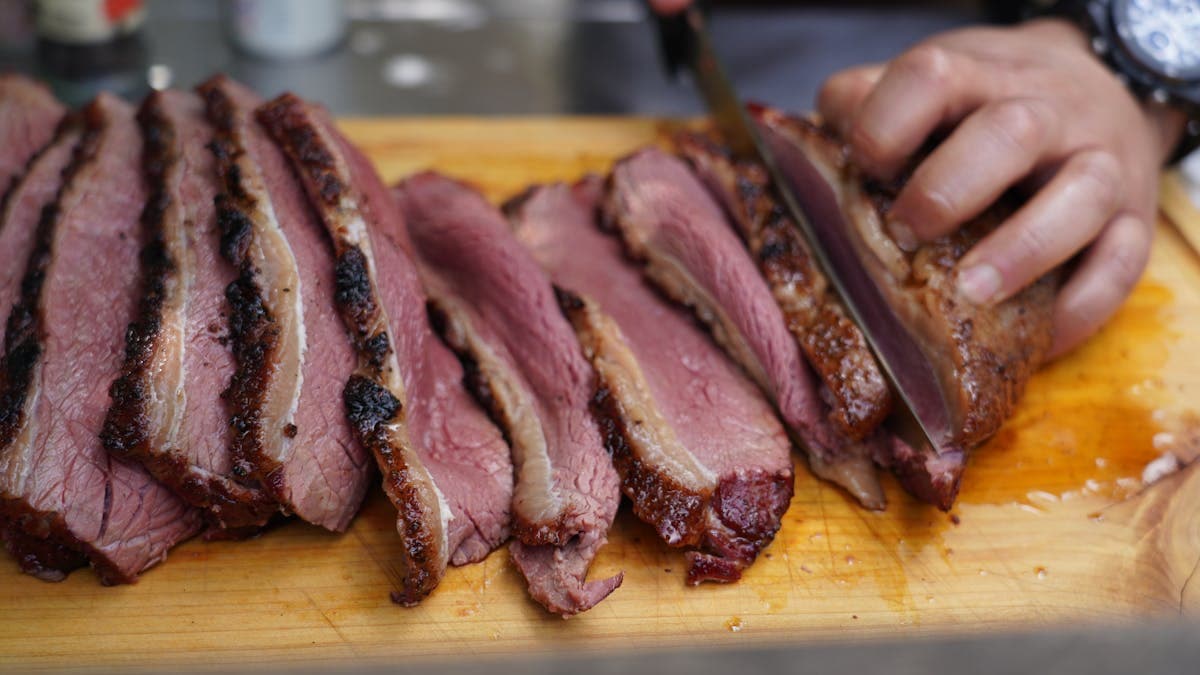 Perfectly smoked beef brisket sliced on a cutting board